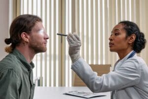 urgent care doctor checking patient's eye with flashlight